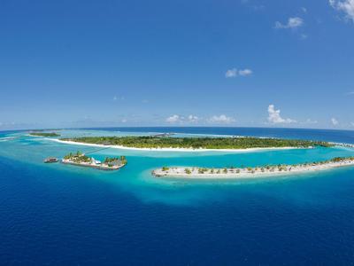 Tropische Insel im klaren blauen Meer mit Sandstrand und grünem Bewuchs unter blauem Himmel.
