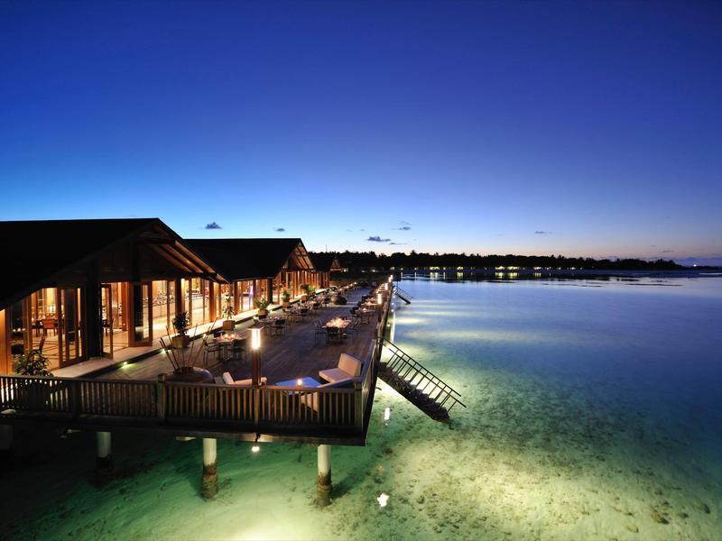 Hotel am Wasser mit beleuchteter Terrasse und klarem Wasser bei Dämmerung