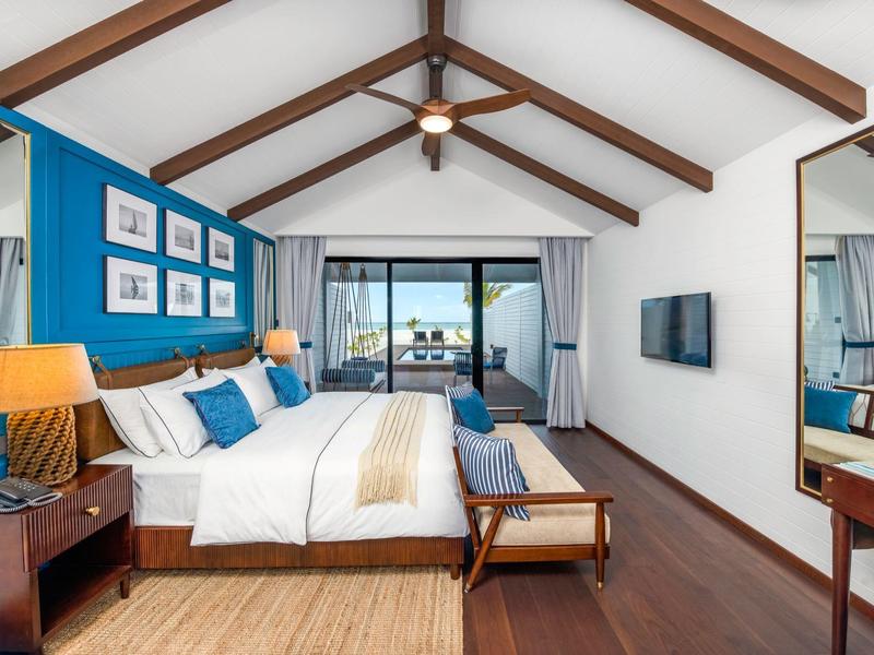 Modernes Hotelzimmer mit Doppelbett, Holzbalkendecke und Blick auf Balkon und Meer.