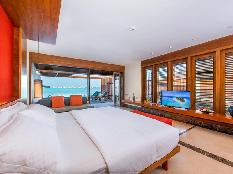 Modernes Hotelzimmer mit großem Bett, Holzwänden und Meerblick durch große Fenster.