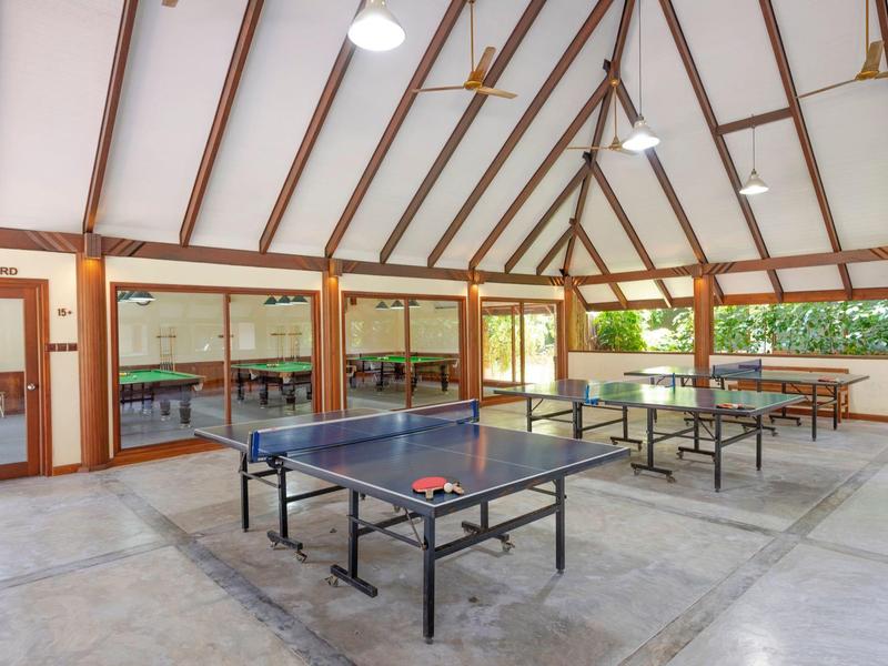 Großer Pavillon mit mehreren Tischtennistischern und Flügeltüren zu einem Garten.