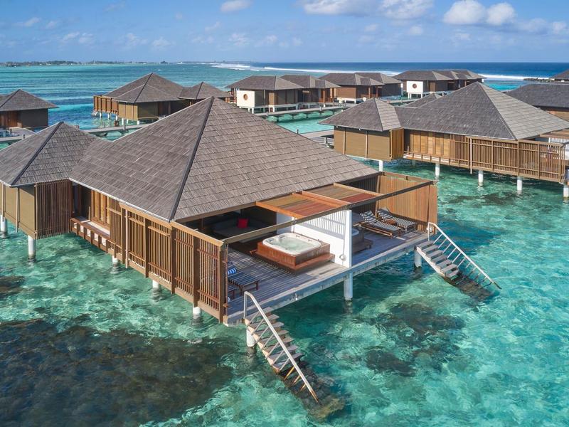 Bungalows auf Pfählen über klarem, türkisfarbenem Wasser mit Treppen und Sonnendecks.