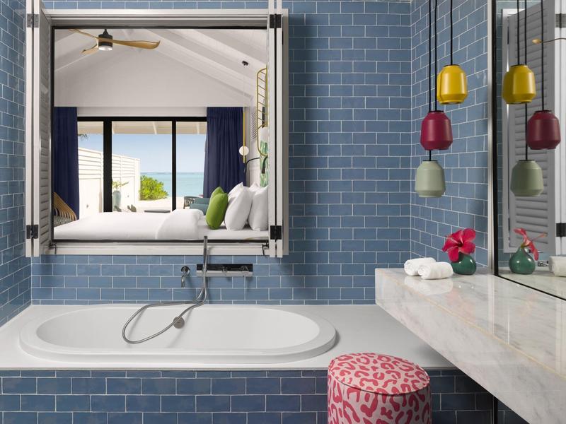 Moderner Badezimmerbereich mit weißer Badewanne, blauen Fliesen und großem Spiegel über Waschbecken.