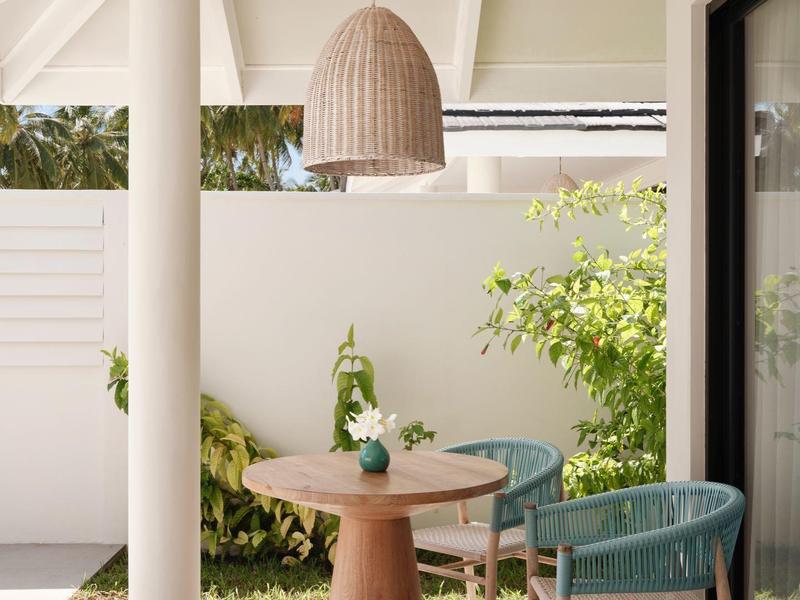 Moderner Balkon mit rundem Holztisch, zwei blauen Stühlen und einer großen Lampenfassung.