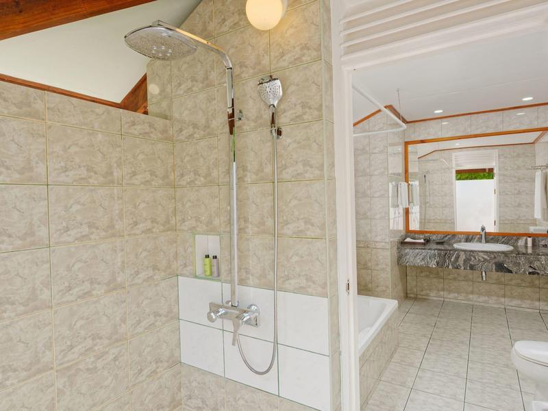 Helles Badezimmer mit Dusche, Wanne, großen Spiegeln und Marmorwaschbecken.