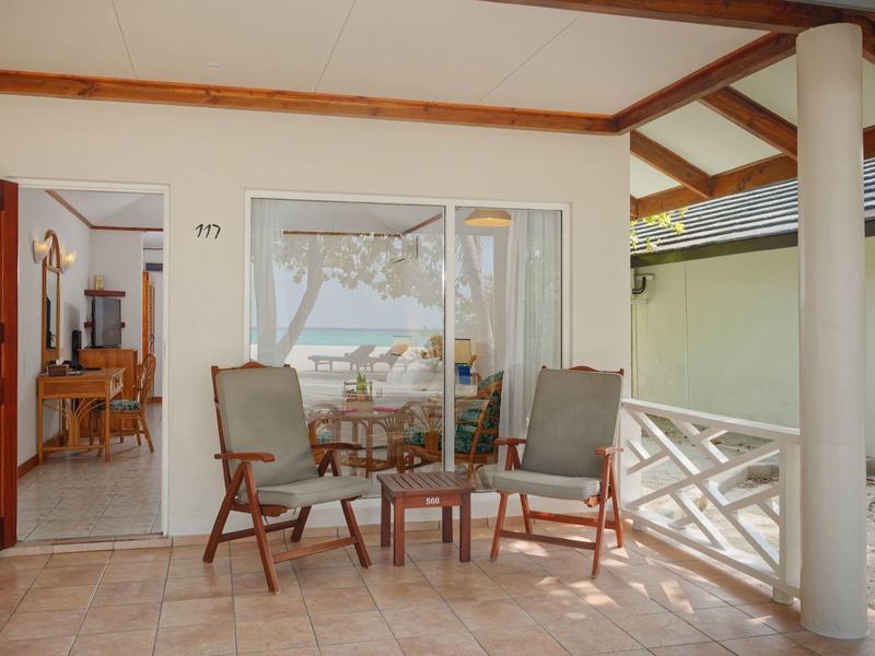 Terrasse mit zwei Sesseln und einem Glas-Tisch mit Blick auf das Meer und das Zimmer dahinter