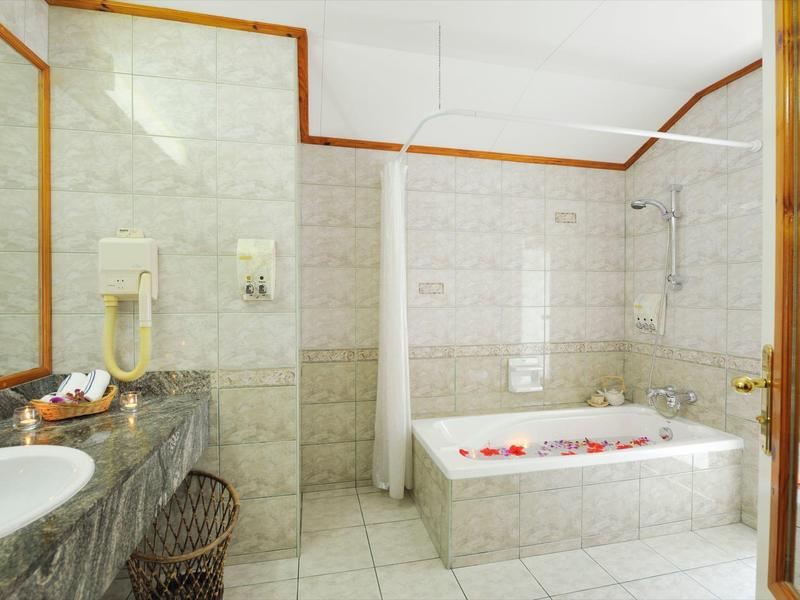 Helles Badezimmer mit Badewanne, Waschbecken und grauem Marmorwaschtisch.