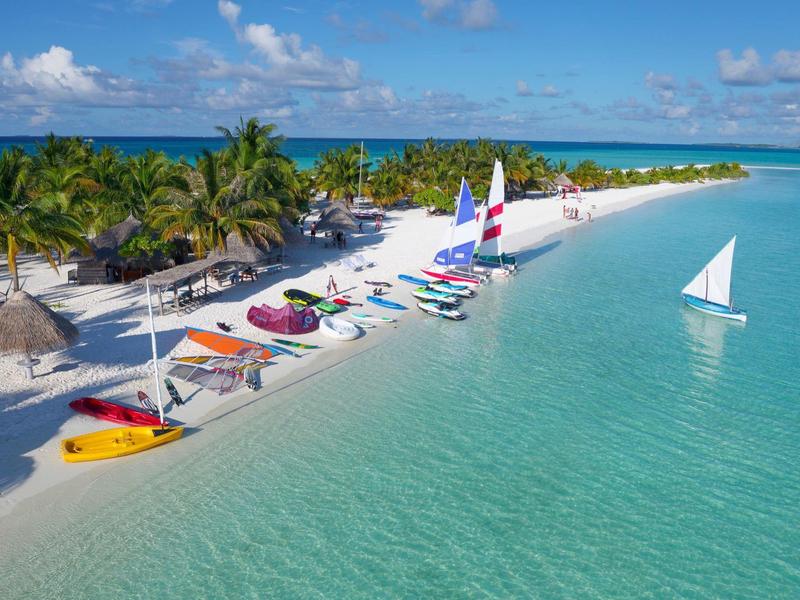 Tropischer Strand mit klarem Wasser, Palmen und bunten Kajaks am weißen Sandstrand