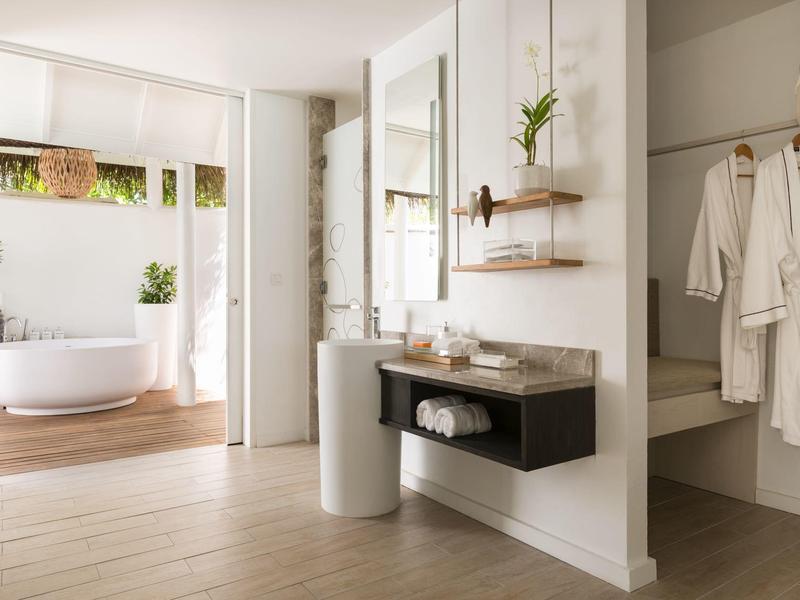 Moderner heller Badezimmerbereich mit freistehender Badewanne und offenem begehbarem Kleiderschrank.