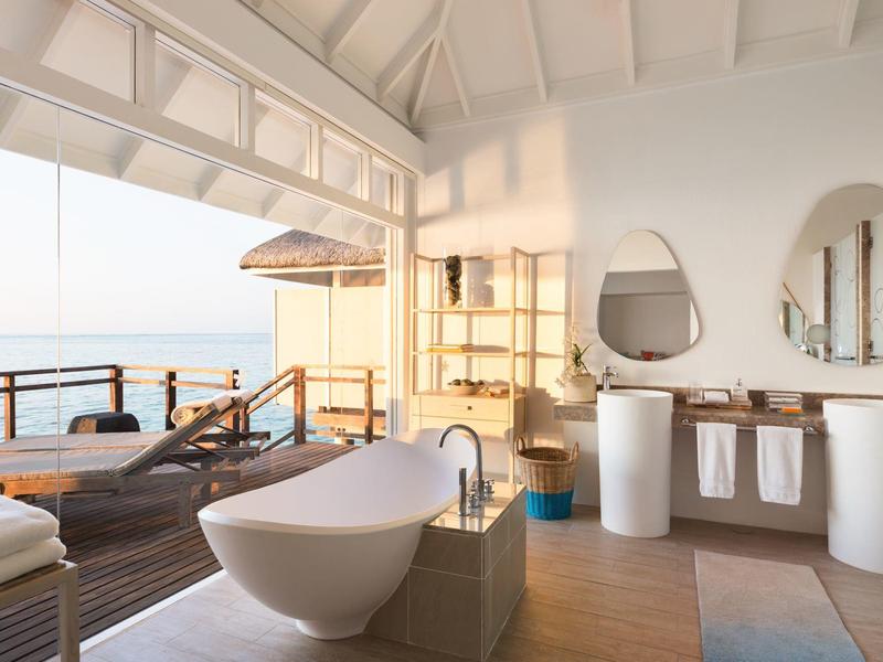 Geräumiges Badezimmer mit freistehender Badewanne, Holzfußboden und offener Terrasse mit Meerblick.