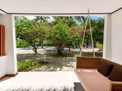 Schattige Veranda mit Korbschaukel und Blick auf einen grünen Garten bei Sonnenschein.