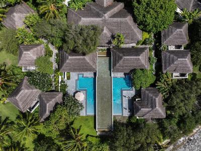 Vogelperspektive auf eine tropische Resortanlage mit mehreren Bungalows und einem zentralen Pool.