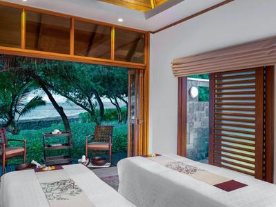 Modernes Zimmer mit zwei Betten und Blick auf einen bewaldeten Garten und Wasser.