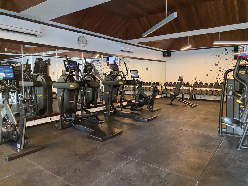 Modernes Fitnessstudio mit Laufbändern, Hanteln und Kraftgeräten in einem gut beleuchteten Raum.