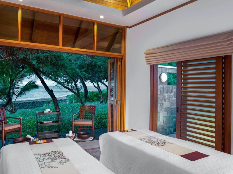 Modernes Zimmer mit zwei Betten und Blick auf einen bewaldeten Garten und Wasser.