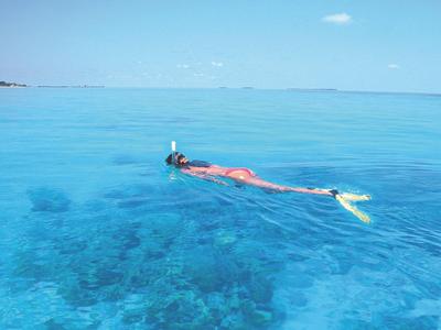 Vogelperspektive auf eine Terrasse über klarem blauem Wasser mit Tisch und Stühlen.