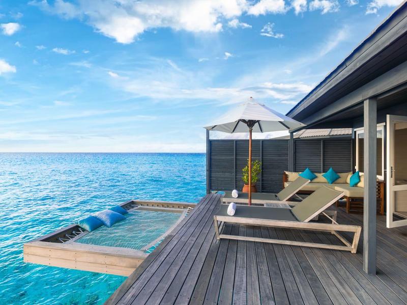 Terrasse mit Sonnenschirmen und Liegestühlen über dem blauen Meer gesäumt von einem Infinity-Pool.