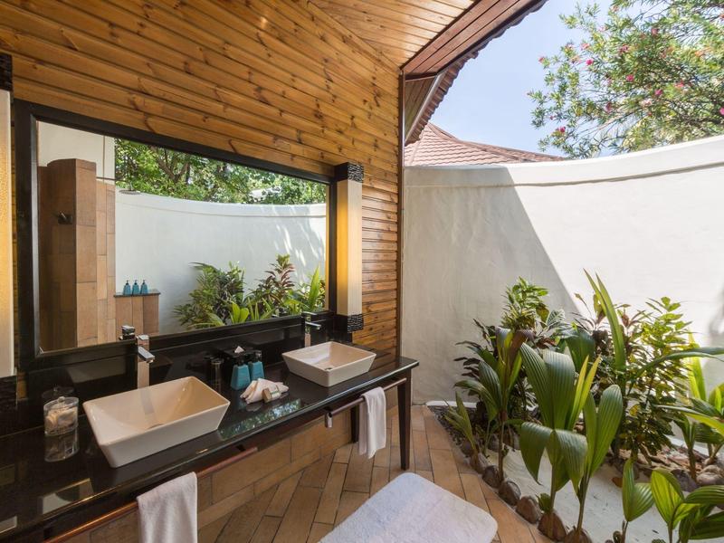 Modernes Badezimmer mit zwei weißen Waschbecken, Holzwand und Blick auf einen kleinen Garten.