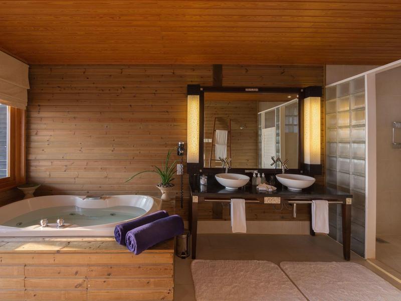 Modernes Badezimmer mit Holzverkleidung, Whirlpool, Doppelwaschtisch und separater Dusche.