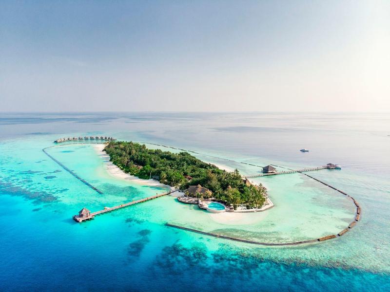 Kleine tropische Insel mit grüner Vegetation und türkisblauem Wasser im Meer.
