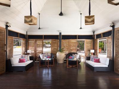 Salon lumineux et aéré avec sol en bois, canapés blancs et grandes fenêtres avec volets en bois.