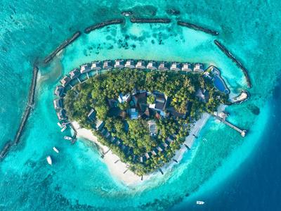 Vue aérienne d'une petite île tropicale avec des bungalows entourés d'eau turquoise.