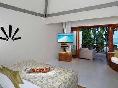 Chambre d'hôtel moderne avec grand lit, balcon et vue sur la mer de jour.