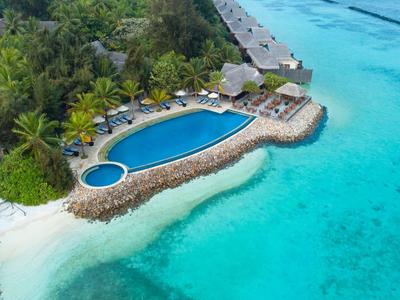 Vue aérienne d'une piscine et d'une jetée sur une plage tropicale avec une eau turquoise claire.