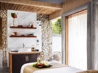 Espace spa confortable avec table de soin, accents en bois naturel et lumière du jour.