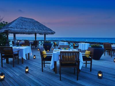 Terrasse de restaurant avec tables et chaises au coucher du soleil au bord de la mer