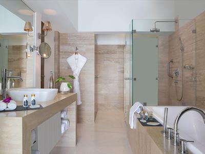 Salle de bains moderne avec baignoire, lavabo et douche à l'italienne dans des tons clairs.