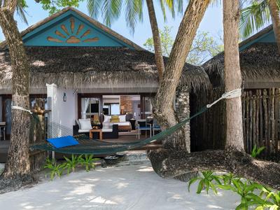 Bungalow de plage avec véranda, hamac et palmiers dans un complexe tropical