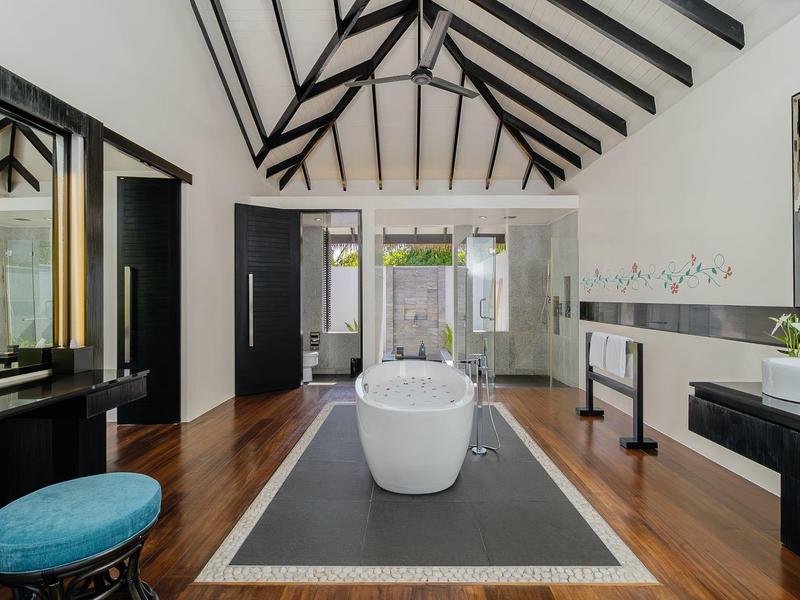 Großes Badezimmer mit freistehender Badewanne, hohen Holzbalken und poliertem Holzboden.