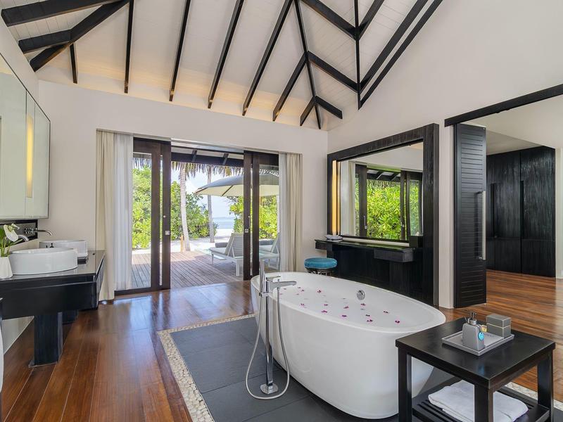 Moderner Wohnraum mit freistehender Badewanne, Holzboden und großen Fenstern Richtung Terrasse.