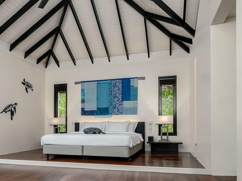 Modernes Schlafzimmer mit hohem Satteldach, weißem Bett, Nachttischen und blauer Wanddekoration.