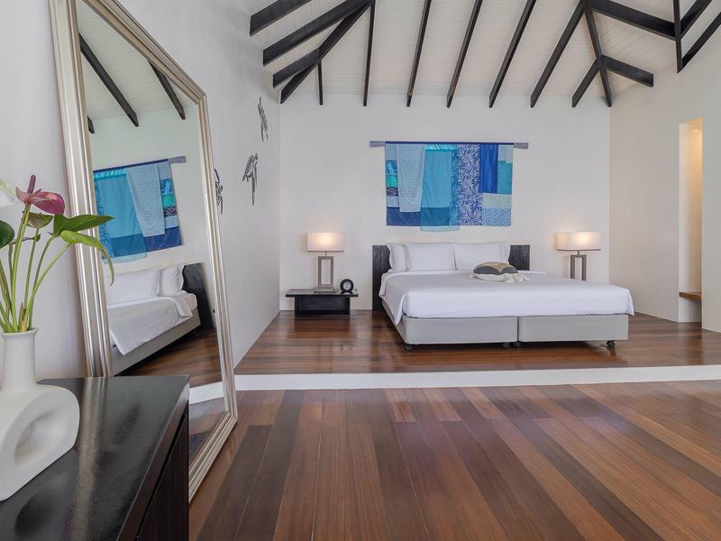 Modernes Schlafzimmer mit Holzboden, Doppelbett, abstraktem Bild und Spiegelwand.