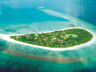 Luftaufnahme einer tropischen Insel mit dichtem Grün und umgeben von weißem Sandstrand und blauem Meer.