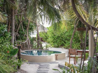 Privater Whirlpool im üppigen tropischen Garten eines Hotels mit Stühlen und grünen Pflanzen