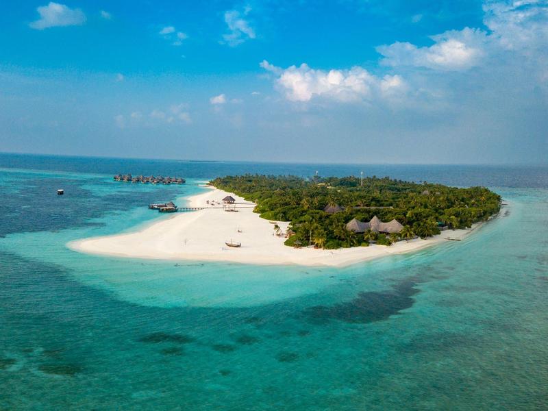 Kleine tropische Insel mit Sandstrand und üppiger grüner Vegetation im klaren blauen Meer.