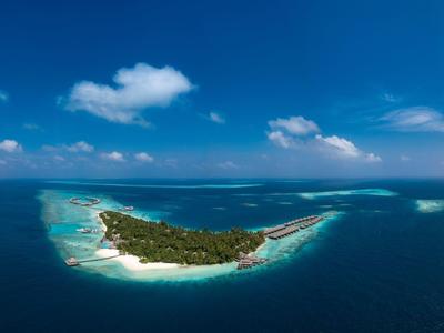 Kleine tropische Insel mit weißen Sandstränden umgeben von türkisfarbenem Meer und blauem Himmel.