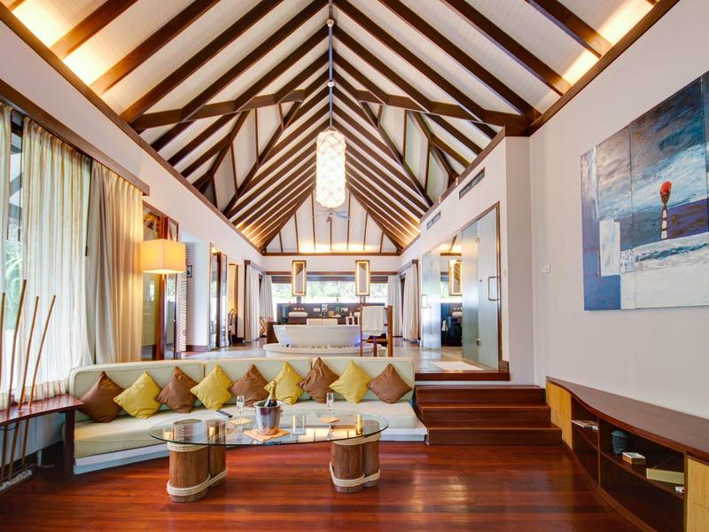 Großes Wohnzimmer mit Holzdecke, bequemer Sofa, Glas-Couchtischen und moderner Beleuchtung.