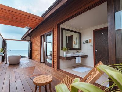 Moderne Terrasse mit Holzverkleidung, Liegestuhl und Blick auf Badezimmer und Meer.