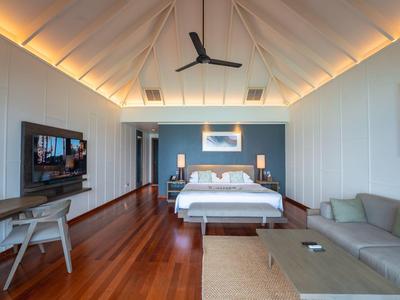 Elegantes Hotelzimmer mit Holzboden, großem Bett, Sofa und TV an der Wand.