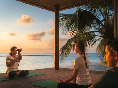Entspannte Menschen meditieren auf einer Terrasse am Meer bei Sonnenuntergang.