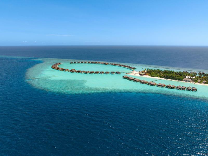 Inselresort mit Wasserbungalows über klarem türkisfarbenem Wasser und tiefblauem Meer.