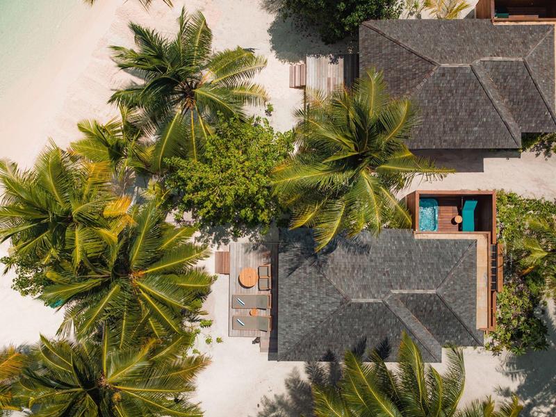 Vogelperspektive auf ein Resort mit Pool, Palm Bäumen und weißem Sandstrand.