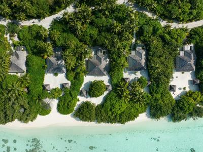 Luftaufnahme von fünf Villen am Strand mit weißem Sand und klarem türkisfarbenem Wasser