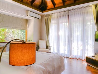 Helles Hotelzimmer mit weißem Bett, grünem Vorhang und modernem Fernseher neben bodentiefen Fenstern.