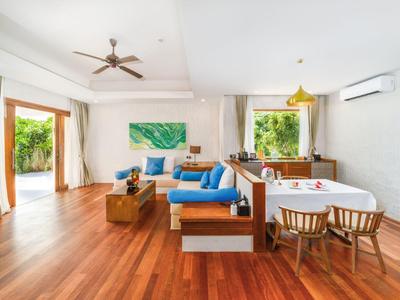 Helles Wohnzimmer mit Holzboden, blauen Sofas, Esstisch und viel natürlichem Licht.