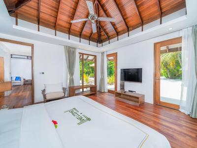 Modernes Hotelzimmer mit Holzboden, Deckenventilator und großem Fenster mit Blick auf tropische Pflanzen.